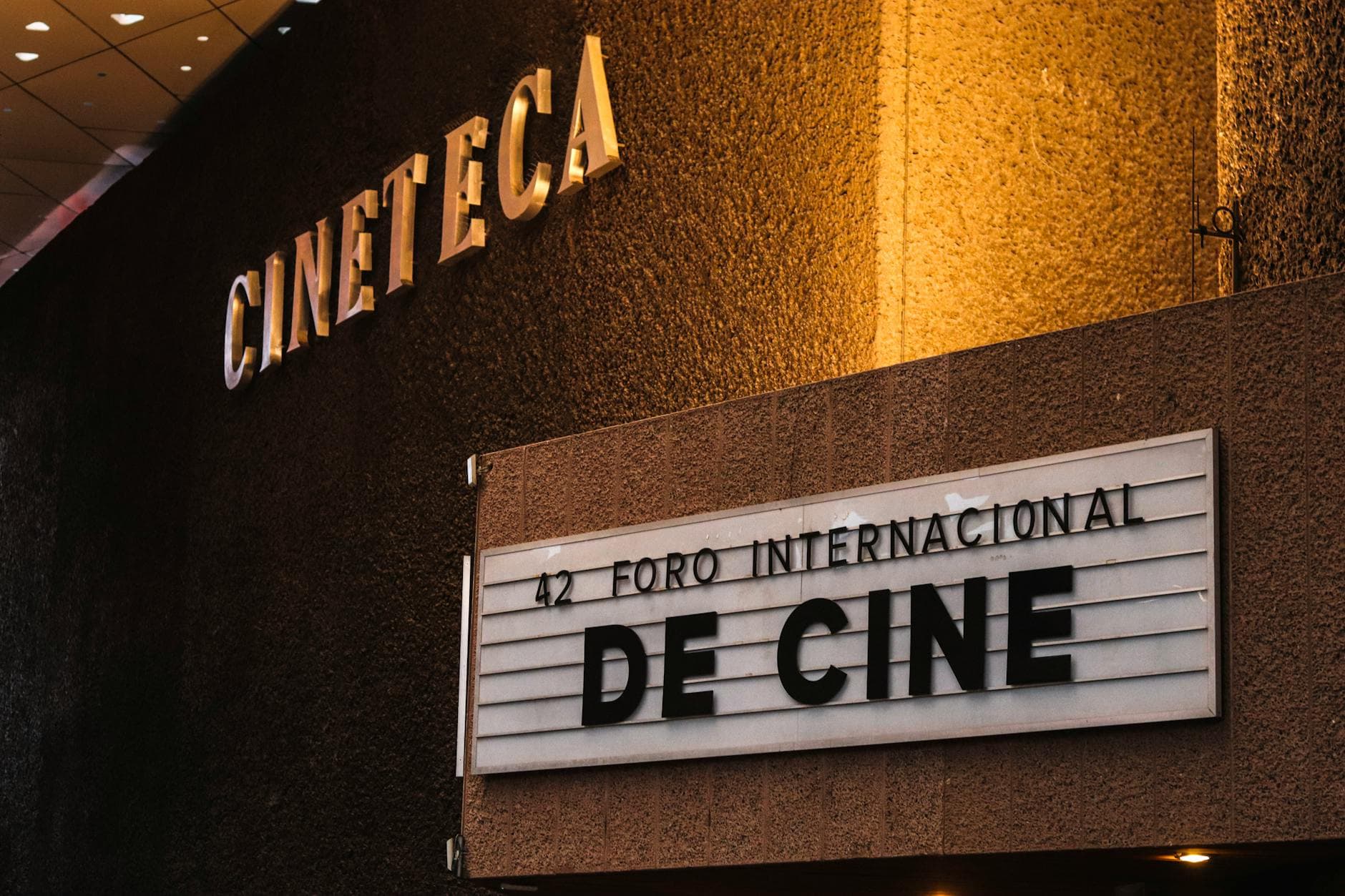 Goldene CINETECA-Leuchtschrift an Gebäudefassade über Schild mit der Aufschrift 42 FORO INTERNACIONAL DE CINE.