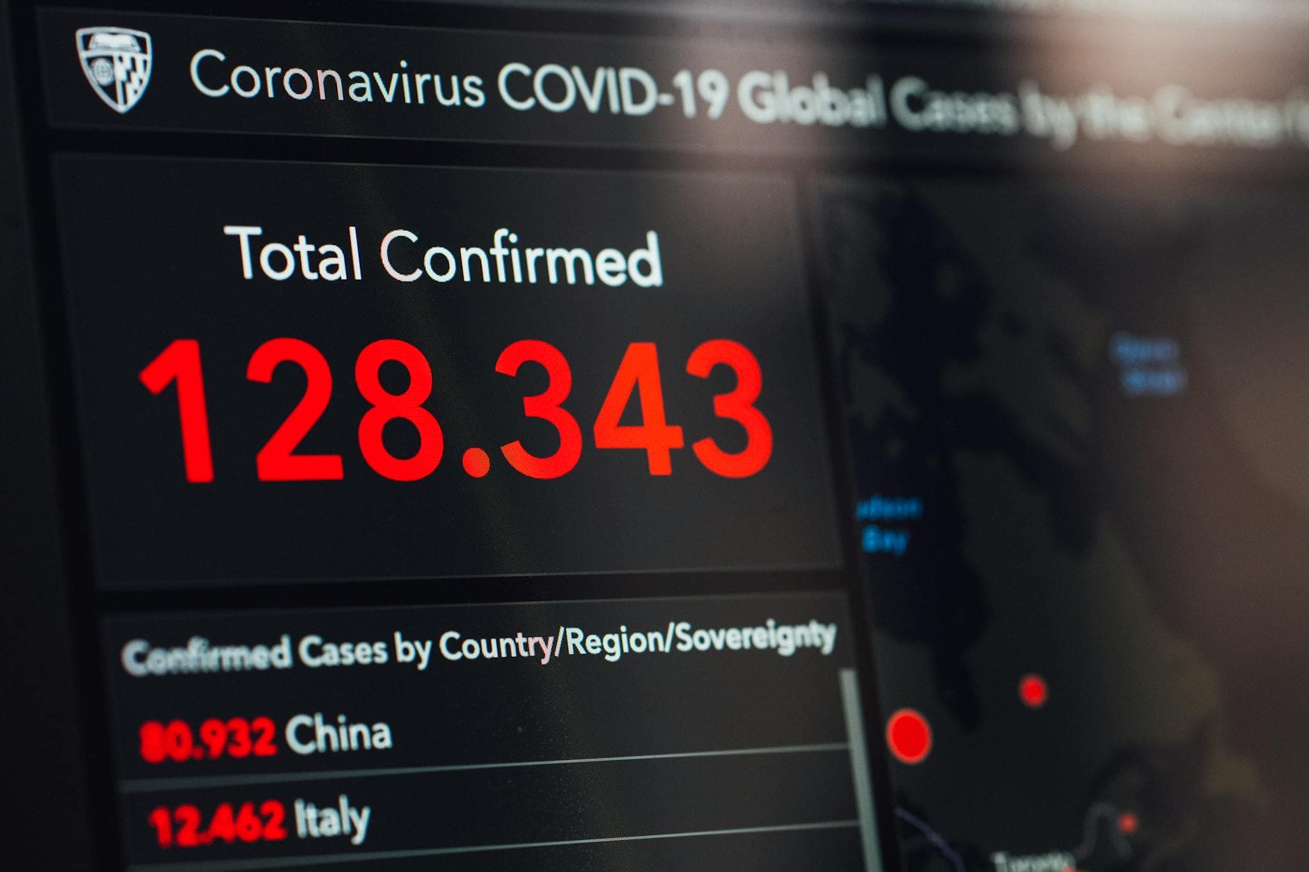 Bildschirm mit COVID-19-Fallzahlen: 128.343 bestätigt, davon 80.932 in China und 12.462 in Italien, sowie Weltkarte.